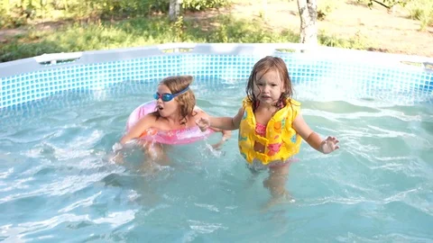 Two sisters swim in a small inflatable pool. Summer in the village. Happy family Stock Footage 94143523