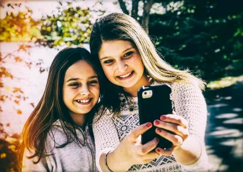 Two sisters taking a self-portrait of themselves during a family outing in a cit Stock Photos