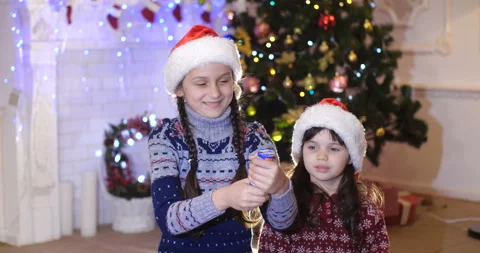 Two sisters trying to shoot from cracker under Christmas tree Видео 131506111