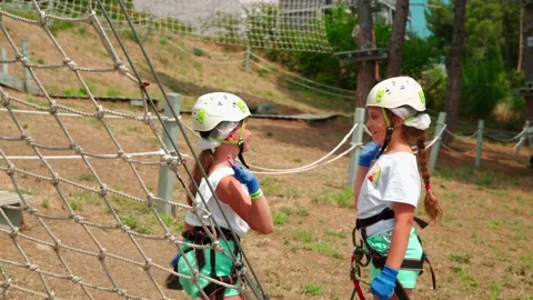 Two sisters walk an obstacle course in a rope park and give each other five Video stock 133605996
