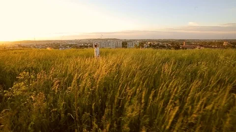 Two sisters walking in a field during sunset holding gands Stock Footage 76362772
