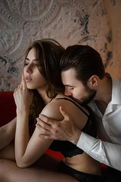 The two sit on a cozy sofa in a dimly lit room, showing a picture of desire.. Stock Photos