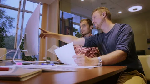 Two sit in the office, look in the computer and discuss the working plan Stock Footage 58015925
