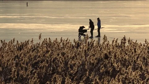 Two skaters go with a stroller on a lake in Sweden Stock Footage 72985376