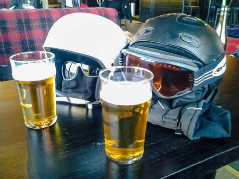 Two ski helmets enjoying two beers Stock Photos