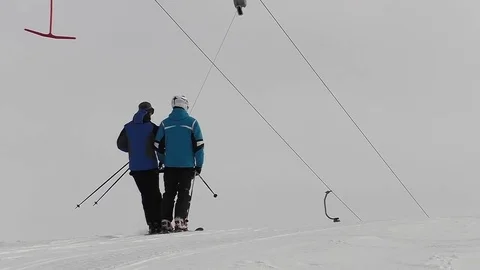 Two skiers are going up by ski lift and are going out Stock Footage 72476128
