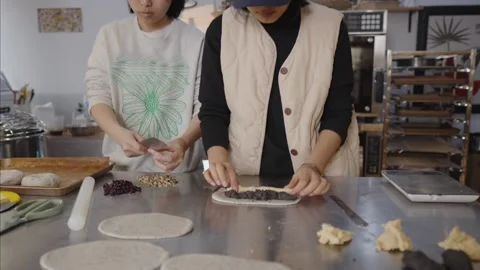 Two skilled female bakers collaborating in commercial kitchen. Meticulously Stock Footage 328992056