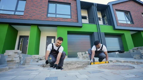 Two skilled workers laying paving stones with precision Stock Footage 293635200