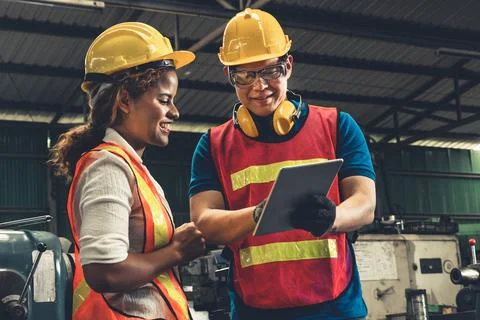 Two skillful factory engineer or worker discussing project on tablet computer Stock Photos