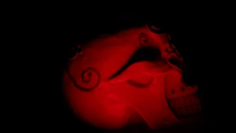 Two Skulls bathed in red light turns to camera close up Stock Footage 114086693