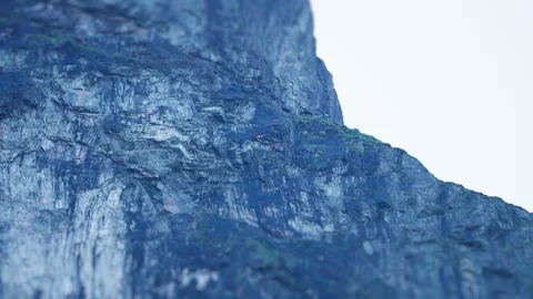 Two skydivers jump off the cliff and descend gliding slowly. Pan follow. Stock Footage 280233337