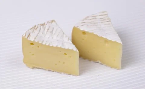 Two slice of round brie cheese out over white corrugated background. Stock Photos