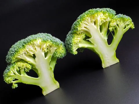 Two sliced broccoli sprigs on a black background close up Stock Photos