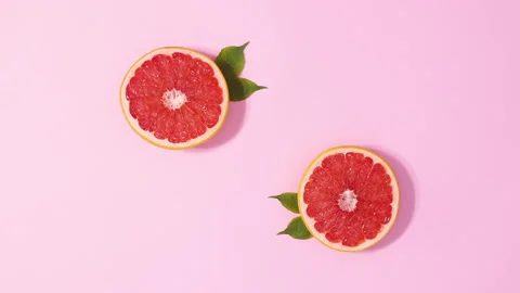 Two sliced fresh grapefruits with green leaves appear Stop motion flat lay 動画素材 152902149