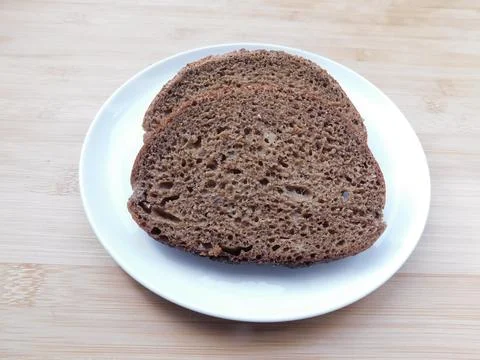 Two sliced slices of bran bread with a crisp crust of rye flour, lying on a b Stock Photos