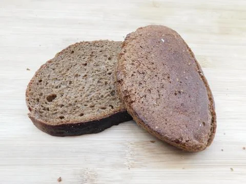 Two sliced slices of bran bread with a crisp crust of rye flour, lying on a b Foto stock