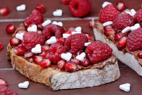 Two slices of bread with chocolate and raspberry on table Stock Photos
