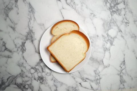 Two slices of bread on white plate on marble background Stock Photos