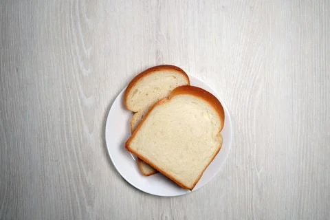 Two slices of bread on white plate on white wooden verneer background Stock Photos