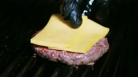 Two slices of cheese putting on grilled beef patty. Stock Footage 101750724