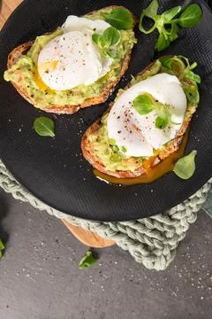 Two slices of crusty toasted bread topped with creamy mashed avocado and pe.. Stock Photos