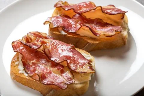 Two slices of fried bread with butter and fried bacon 스톡 사진
