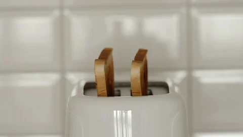 Two slices of roasted bread jump out from a white toaster - Close Up Vídeos de archivo 120769263