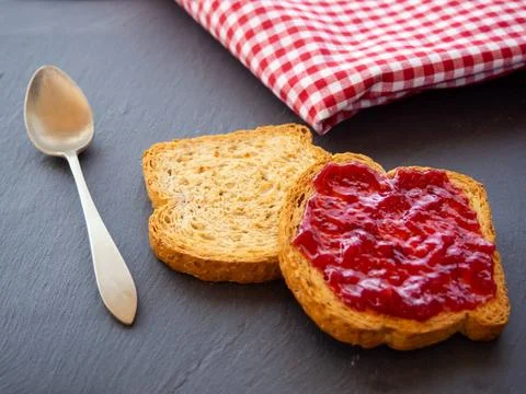  Two slices of toast with raspberry jam on a slate plate, a spoon and a ta... Stock Photos