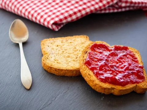  Two slices of toast with raspberry jam on a slate plate, a spoon and a ta... Stock Photos
