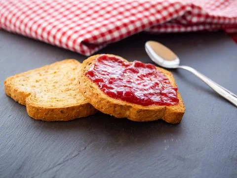  Two slices of toast with raspberry jam on a slate plate, a spoon and a ta... Stock Photos