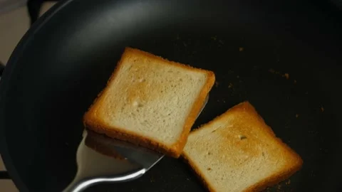 Two slices of toasts cooked in a pan on the stove and tossed over. Cooking Stock Footage 150497943