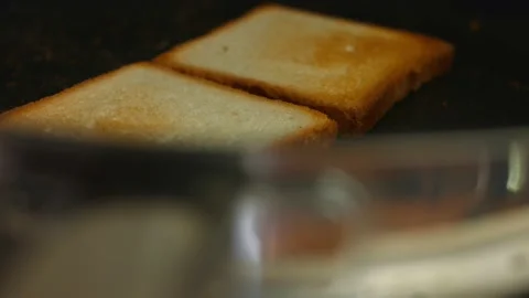 Two slices of toasts cooked in a pan on the stove. Cooking delicious toasts at Stock Footage 150498083