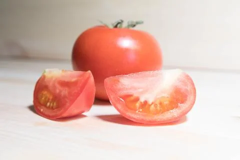 Two slices of tomato against the background of a whole tomato Stock Photos