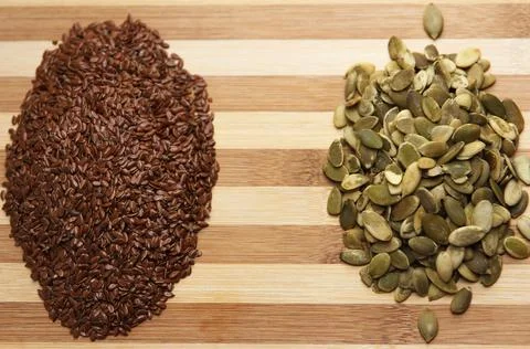 Two slides of dry raw pumpkin seeds and flax, lie a slide on a table Stock Photos