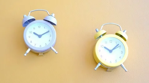 Two small alarm clocks on brown background close-up top view. Stock Footage 302962114