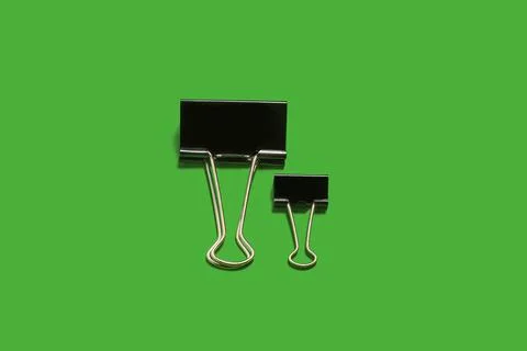 Two small and big paper clips on a green surface Stock Photos