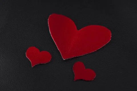 Two small and large red hearts on black skin close-up Stock Photos