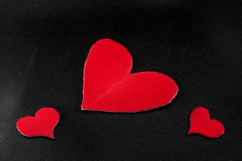 Two small and large red hearts on black skin close-up Stock Photos