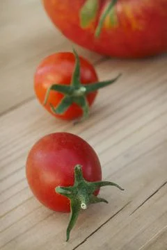Two small and one large ripe tomatoes on a  table Stock Photos