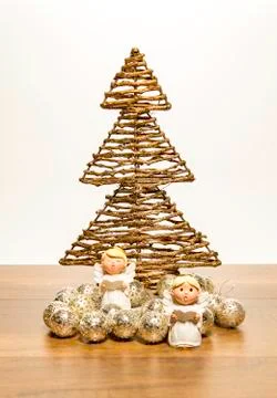 Two small angels stand in front of Christmas tree with silver balls Stock Photos