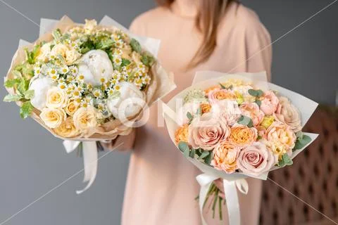 Two Small Beautiful bouquets of mixed flowers in woman hand. Floral shop concept Stock Photos