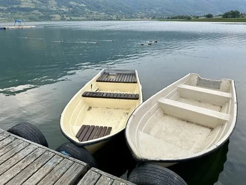Two small boats docked on a tranquil lake with mountains nearby Fotos Stock
