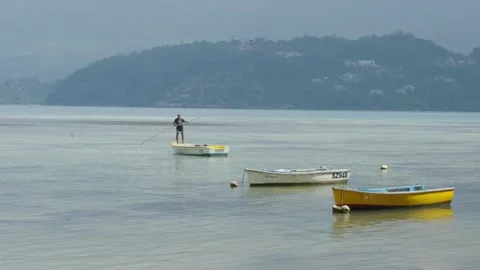 Two small boats floating near shore with mountain view across bay on Mahe Island Stock Footage 331506378