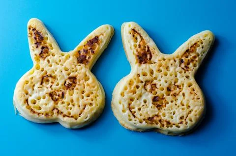 Two small, burnt looking pancakes with rabbit faces on them Stock Photos