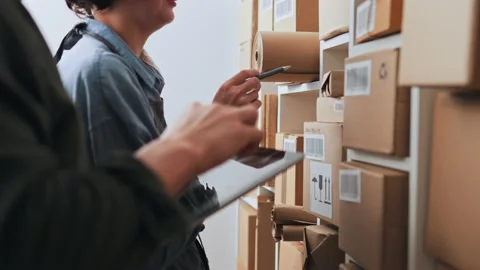 Two small business workers work in a cargo warehouse of barcoded box parcel Stock Footage 224083079