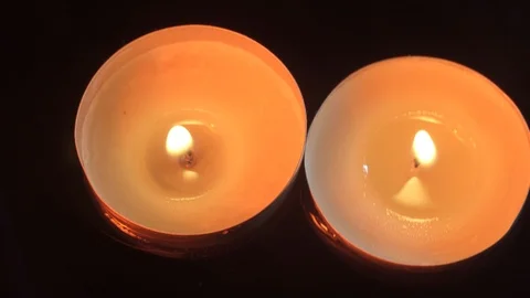 Two small candles float in the water in the darkness, warm tones, top view Stockbeeldmateriaal 114064033