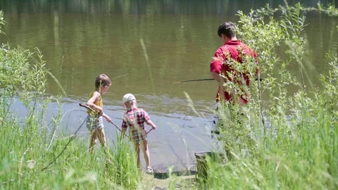 Two small children and a young father fishing on the river Bank. Beautiful Video stock 91391806