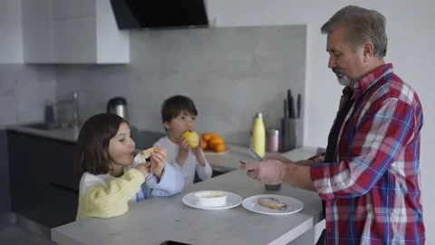 Two small children are eating sandwiches made by grandfather, slow motion Видео 201475617