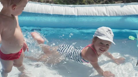 Two small children bathe and frolic in pool in summer Video stock 138101014