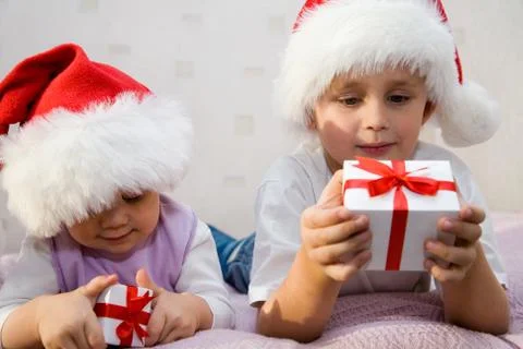 Two small children lie on a sofa and consider the gifts Stock Photos